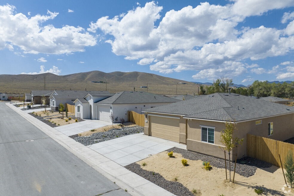 a neighborhood of houses with a street and mountains in the background