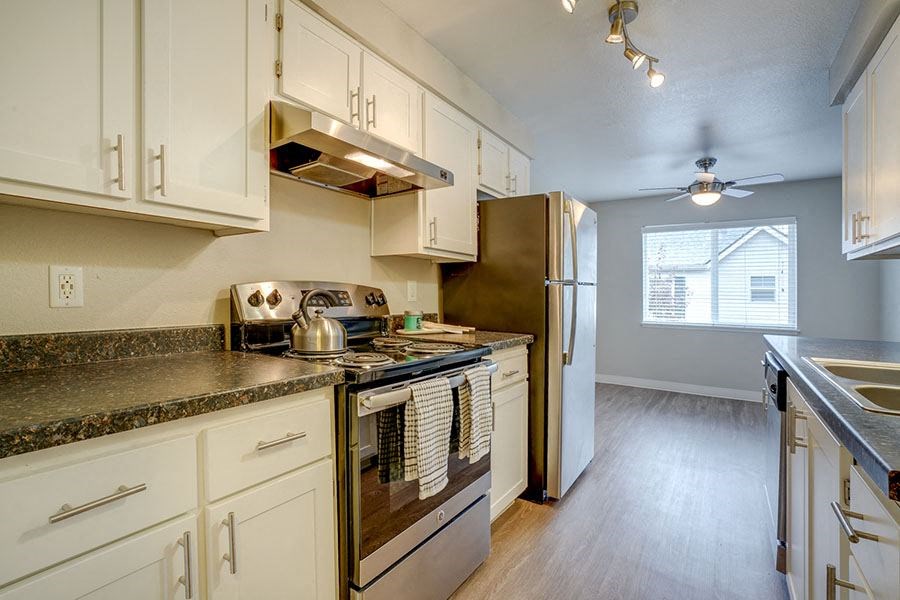 Kitchen with Granite-Style Countertops, White Cabinets, and Appliances at TOWNSHIP Apartments, CANBY