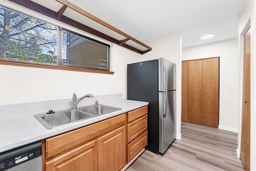 Pet-Friendly Apartments in Kent, WA - Township Lake Meridian - Kitchen with Vinyl Plank Flooring, Stainless Steel Appliances, Solid Wood Cabinets, Granite Countertops, and a Window