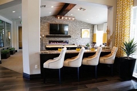 a kitchen with a bar with chairs and a television