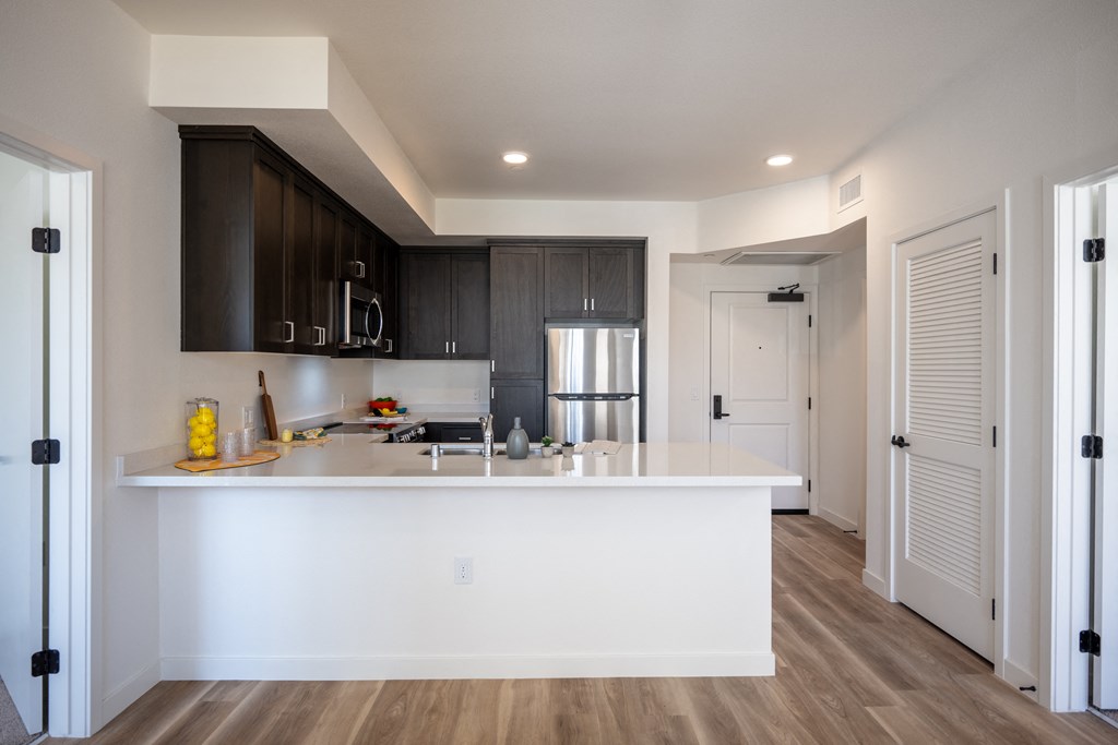 a white kitchen with a large island and dark cabinets at Vintage at Anacapa Canyon, Camarillo, 93012