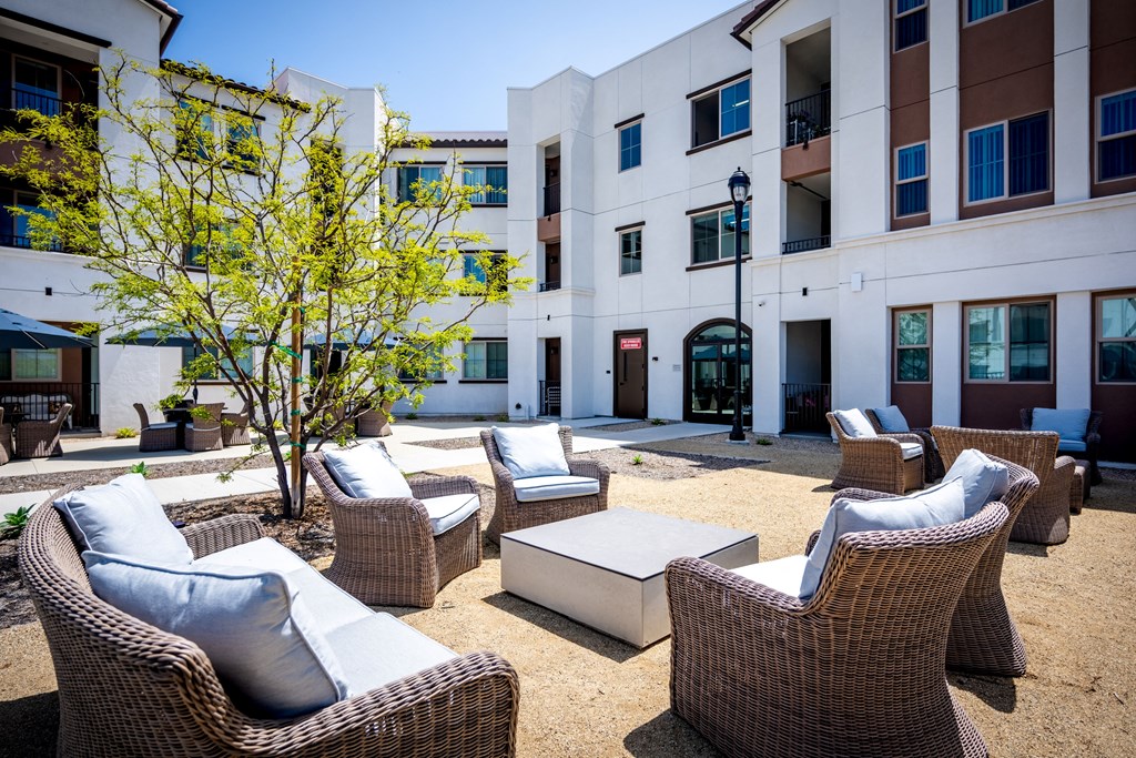 a courtyard with chairs and tables and a building in the background at Vintage at Anacapa Canyon, California 93012