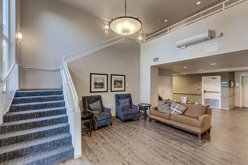 A living room with a couch, chairs, and a staircase.