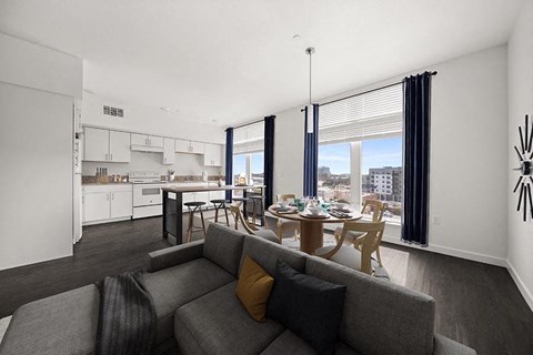 A modern living room with a grey couch and a dining table.