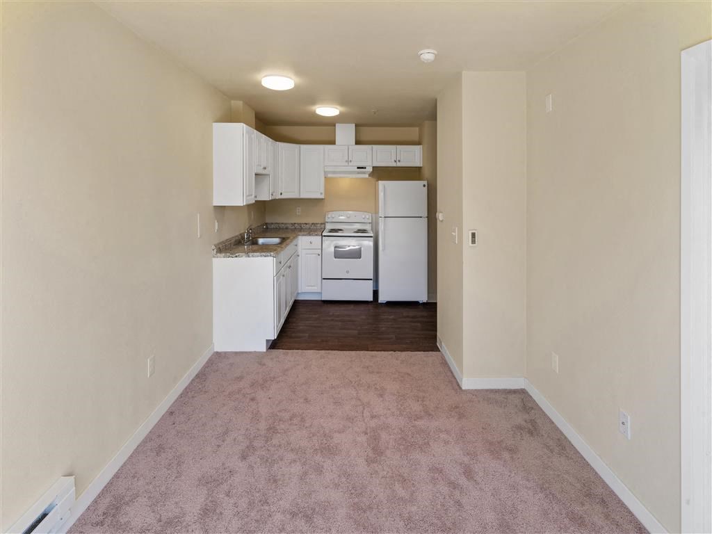 a kitchen with a white refrigerator freezer next to a stove top oven at Webster Court Senior Apartments, Kent Washington