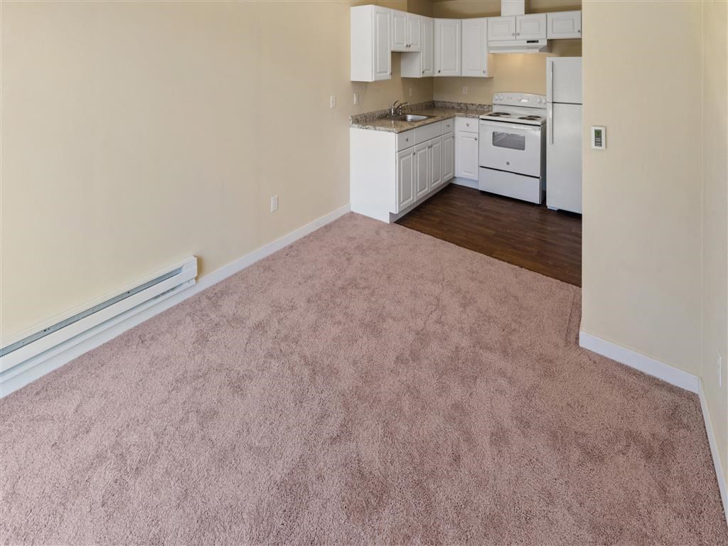 an empty room with a kitchen in the background at Webster Court Senior Apartments, Kent, 98032