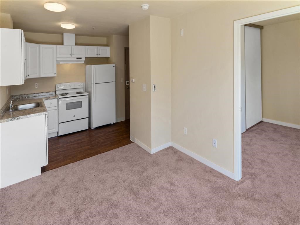 a kitchen with a white stove top oven next to a white refrigerator at Webster Court Senior Apartments, Kent, WA