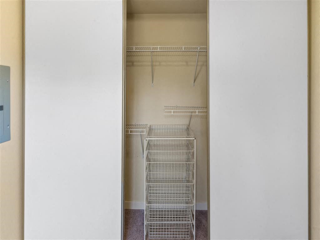 a walk in closet with white racks and a blue sign on the wall at Webster Court Senior Apartments, Kent, 98032