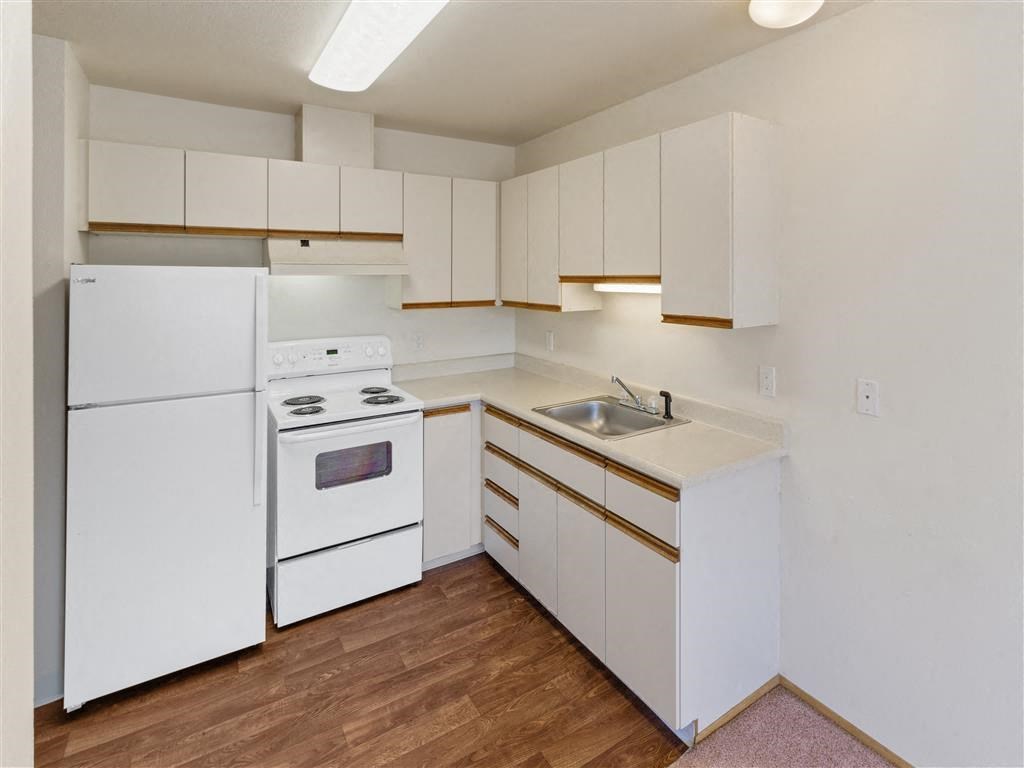 a kitchen with white appliances and white cabinets at Webster Court Senior Apartments, Washington