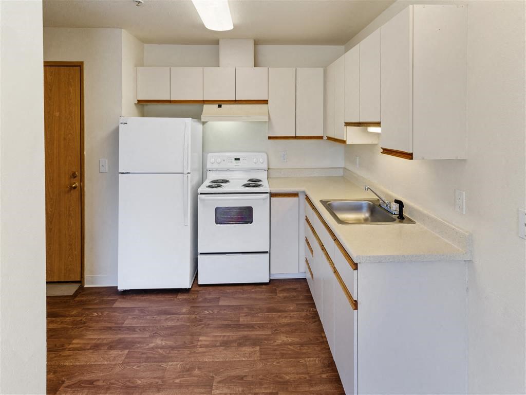 a kitchen with white appliances and a wooden floor at Webster Court Senior Apartments, Kent Washington