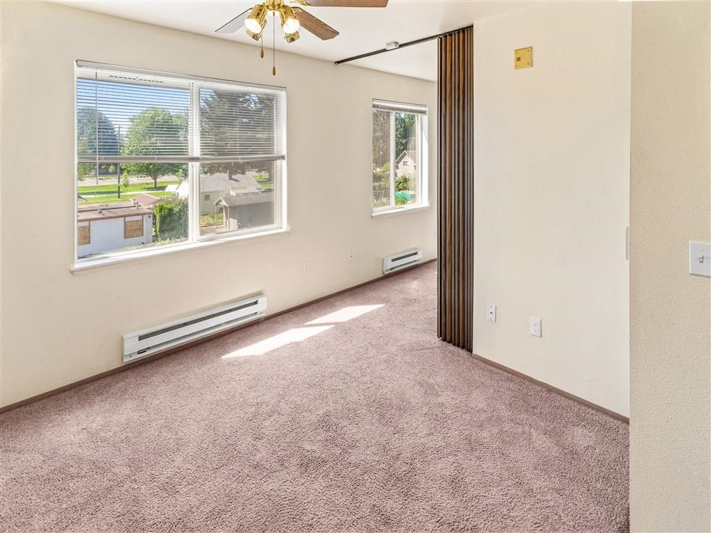 an empty room with a ceiling fan and two windows at Webster Court Senior Apartments, Kent, 98032