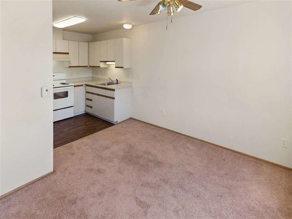 a living room with a ceiling fan and a kitchen in the background at Webster Court Senior Apartments, Kent, 98032