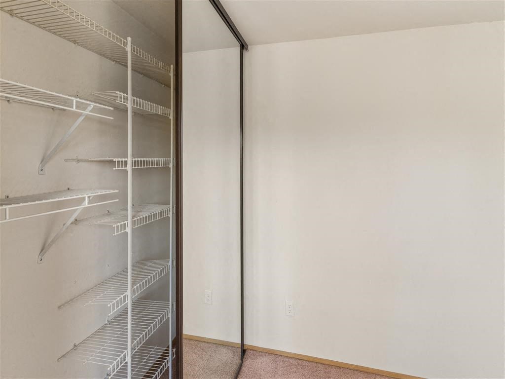 a walk in closet in a bedroom with white walls and a sliding glass door at Webster Court Senior Apartments, Washington