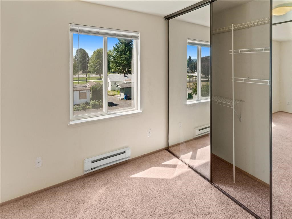 a bedroom with a large window and a mirrored closet at Webster Court Senior Apartments, Kent