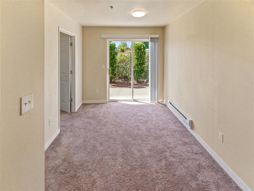 a large room with carpeted floors and a glass door leading to a patio at Webster Court Senior Apartments, Washington