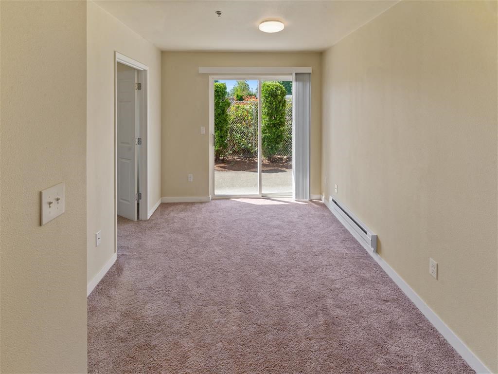 a large room with carpeted floors and a sliding glass door at Webster Court Senior Apartments, Kent