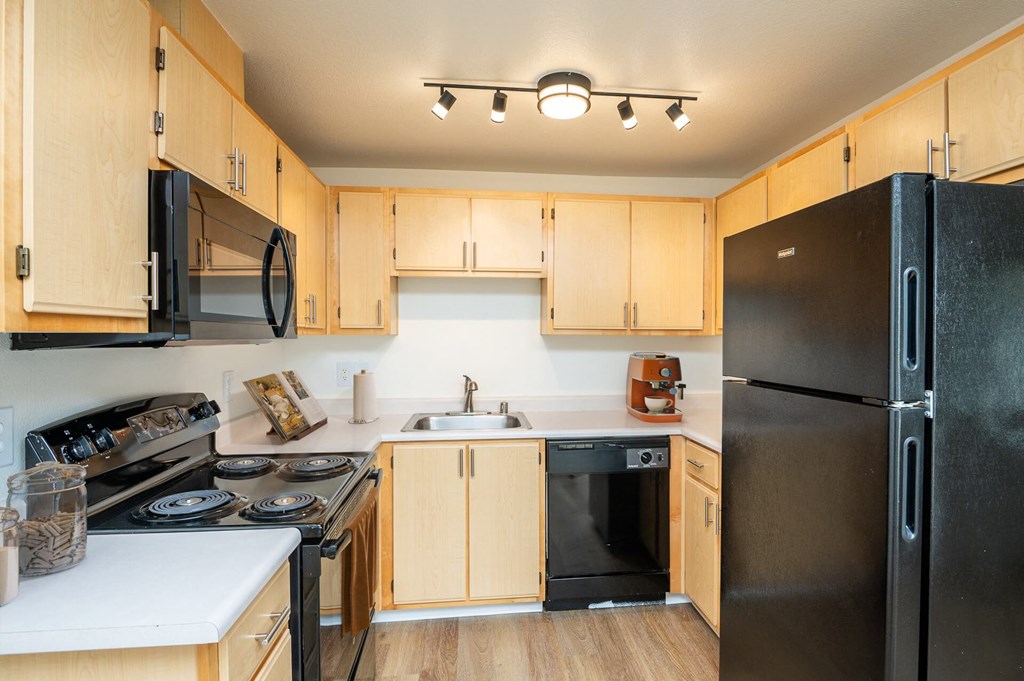 A kitchen with wooden cabinets and black appliances.at Vancouver Mall Apartments, Vancouver