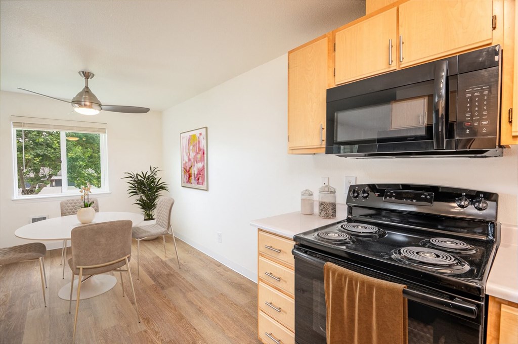 A kitchen with a black stove and a black microwave above it.at Vancouver Mall Apartments, Washington, 98662