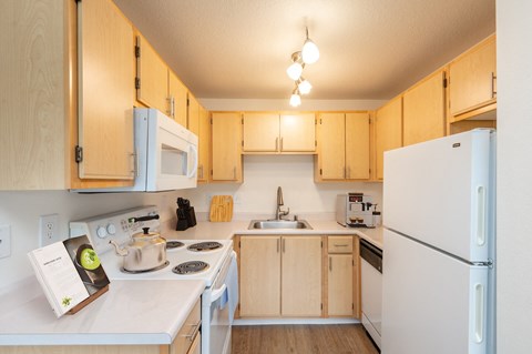 A kitchen with a white refrigerator and wooden cabinets.at Vancouver Mall Apartments, Vancouver, 98662