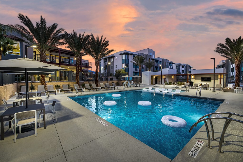 A swimming pool surrounded by palm trees and lounge chairs.