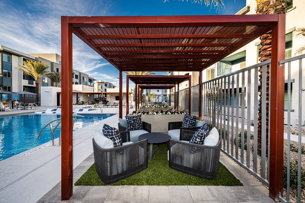 A patio with a pool and a wooden pergola.