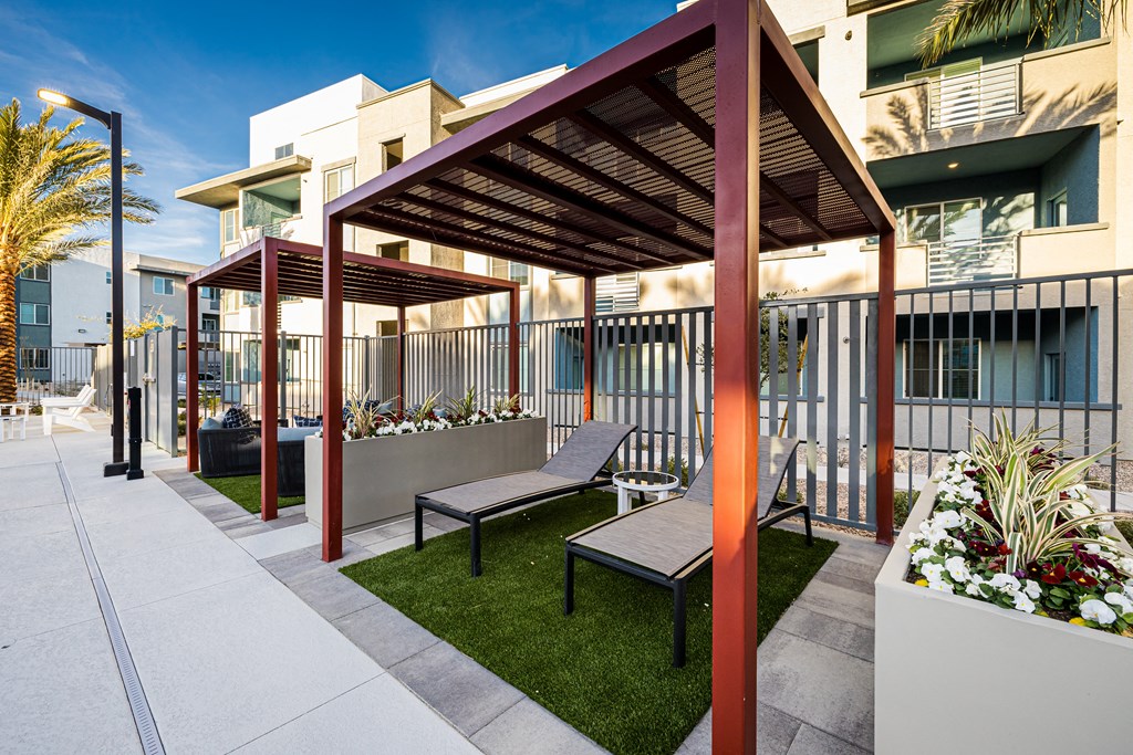 A patio with a bench and a table under a roof.