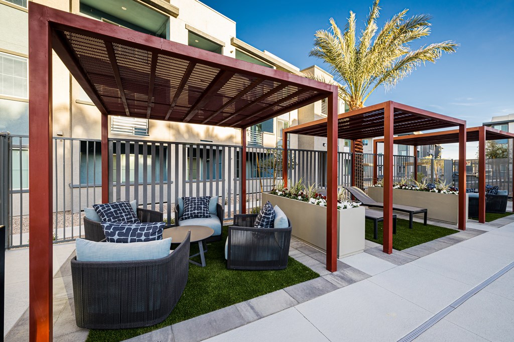 A patio area with a red pergola and grey couches.