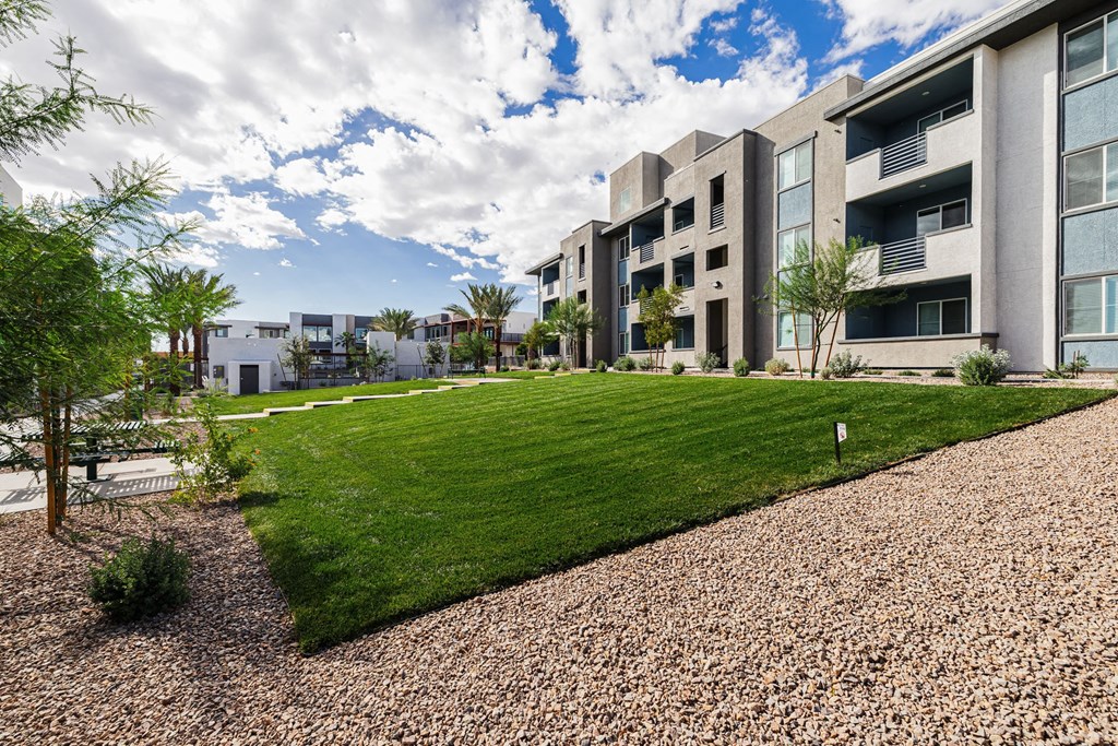 modern apartment buildings with a grassy area and a gravel pathway at BASE APARTMENT HOMES, LAS VEGAS, NV 89166