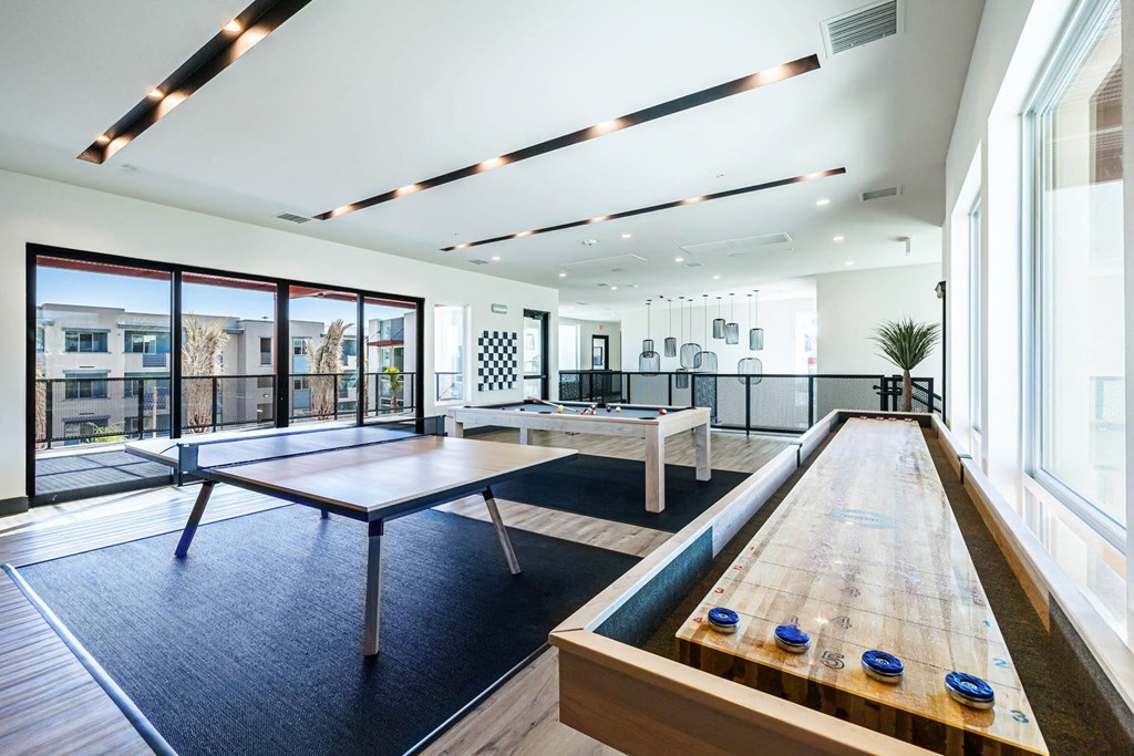 a game room with ping pong tables and windows