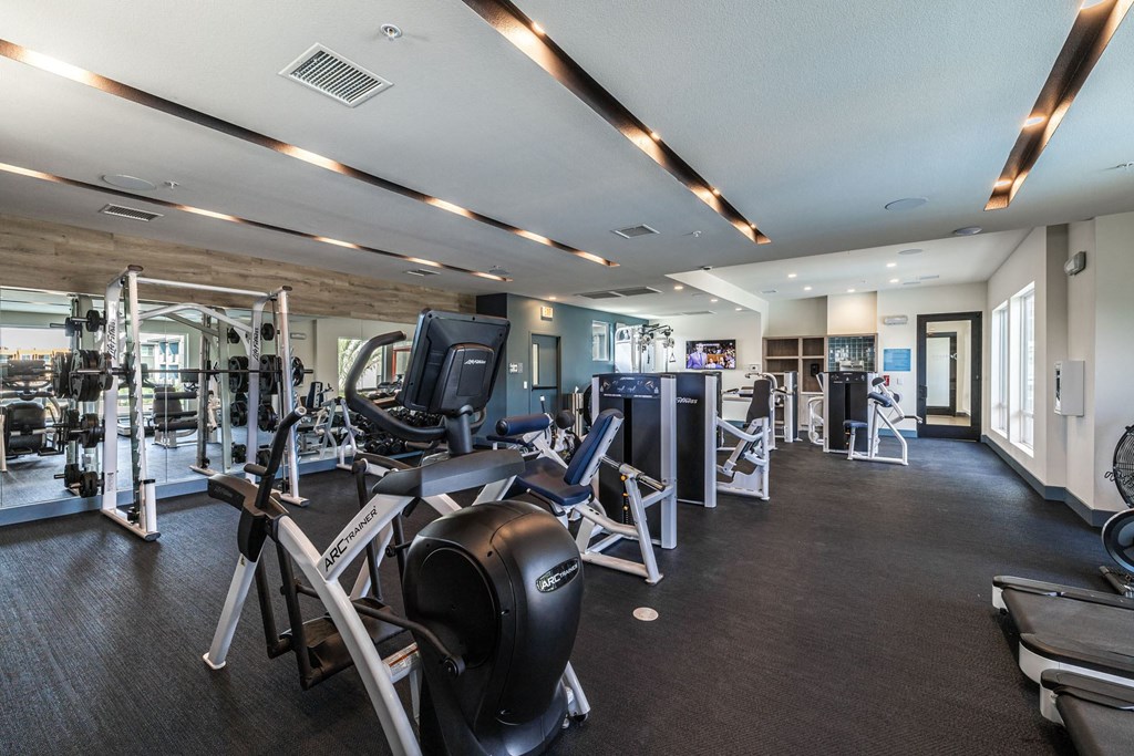 a gym with weights and cardio equipment in a building with glass doors at BASE APARTMENT HOMES, Nevada