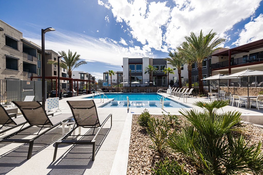 a swimming pool at a hotel with chairs and umbrellas at BASE APARTMENT HOMES, LAS VEGAS, 89166