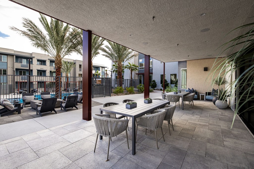 a patio with tables and chairs and palm trees at BASE APARTMENT HOMES, LAS VEGAS, 89166