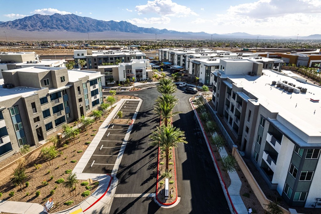 a group of new apartment buildings in a parking lot with mountains in the background at BASE APARTMENT HOMES, LAS VEGAS, Nevada