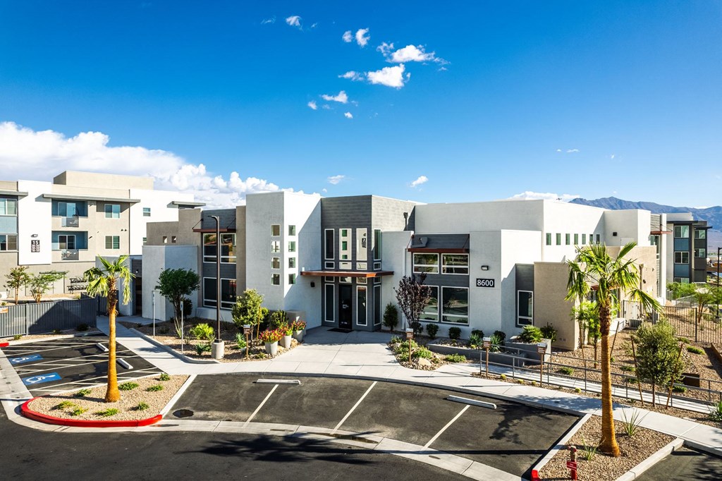 a building with a parking lot and palm trees in front of it at BASE APARTMENT HOMES, LAS VEGAS