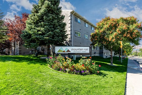 a view of the front of a building with a lawn and flowers at Mountain Run Apartments, Orem, Utah