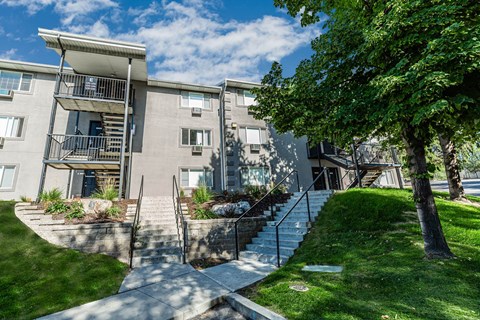 front view of the building with stairs and grass and trees at Mountain Run Apartments, Utah 84058