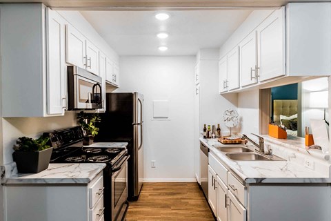 a kitchen with white cabinets and black appliances and a sink