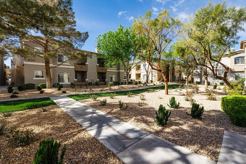 a courtyard with trees and a sidewalk in front of apartment buildings