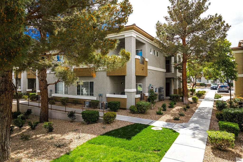 an apartment building with a sidewalk and trees
