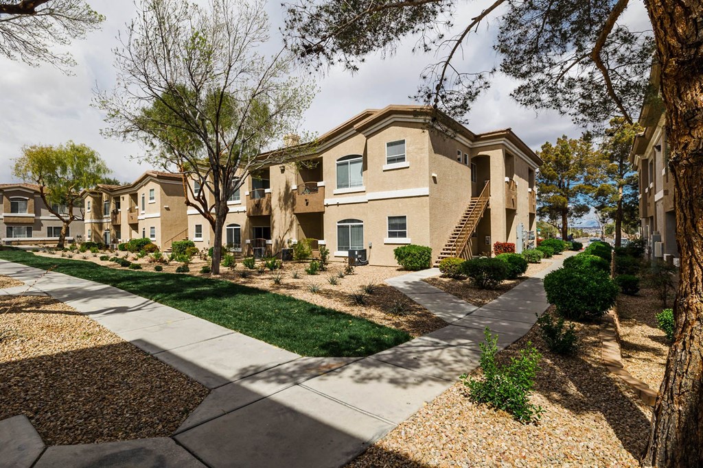 exterior view of multiple apartment buildings with sidewalks and grass and trees