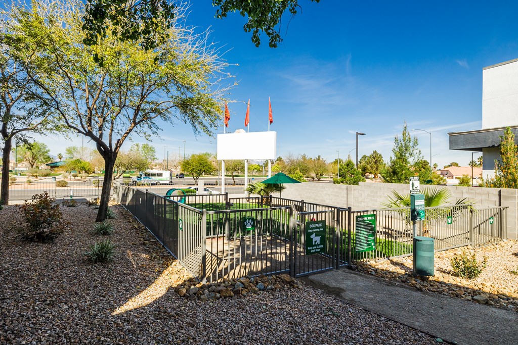 A white sign is on a gate in front of a green bush.