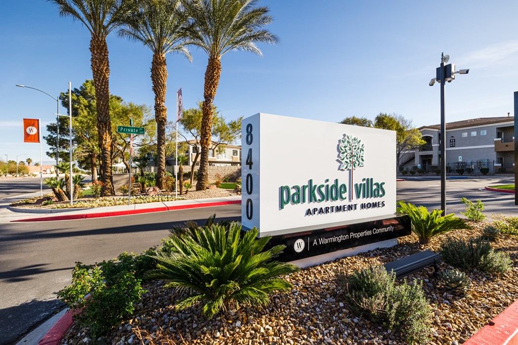A sign for Parkside Villas Apartment Homes is in front of a palm tree.