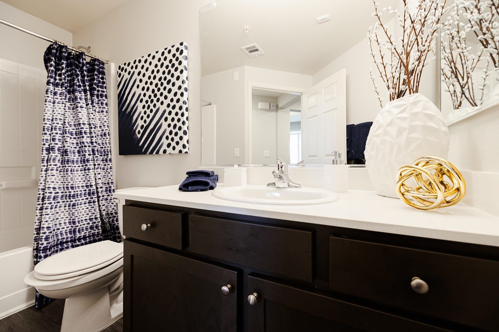 A bathroom with a toilet, sink, and mirror.