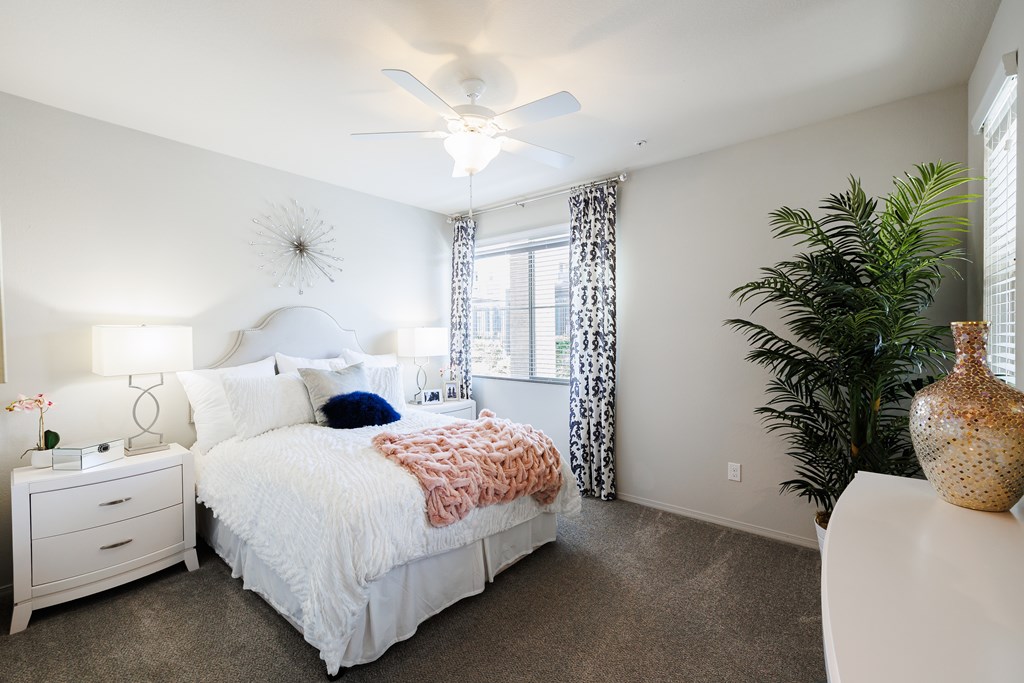 A bedroom with a white bed and a ceiling fan.
