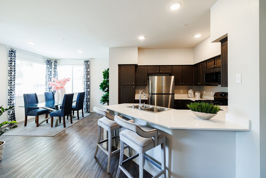 A modern kitchen with a bar stool and a dining table.