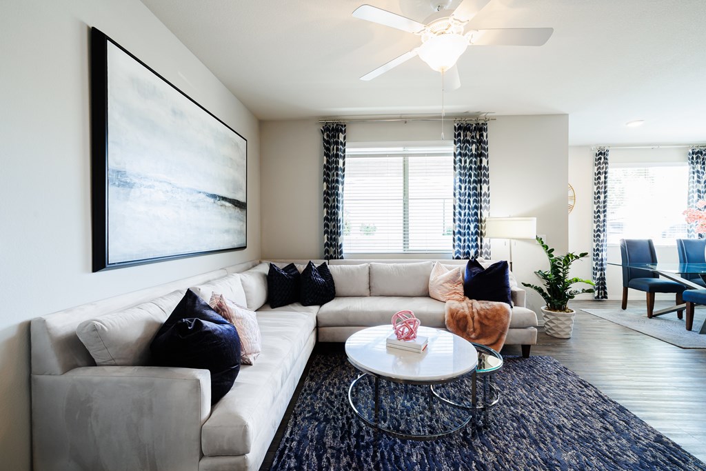 A living room with a white couch, a coffee table, and a painting on the wall.