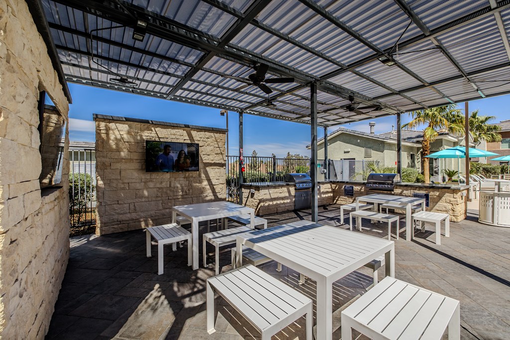 A patio with white furniture and a stone wall.