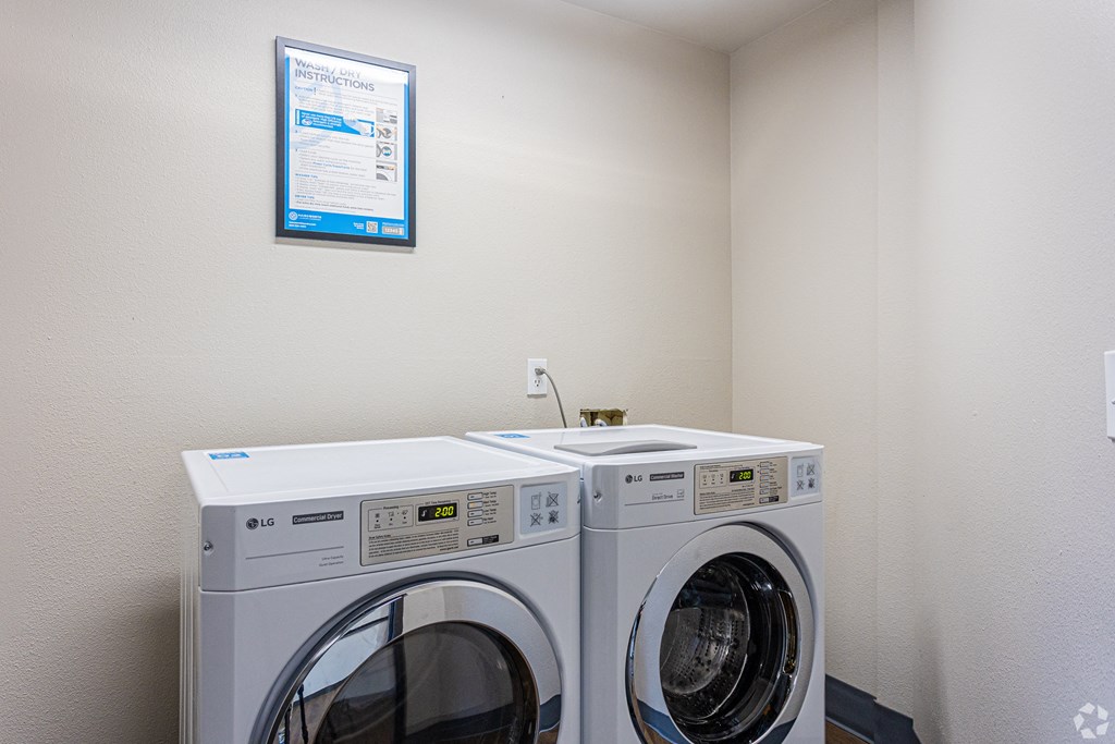 a washer and dryer in a laundry room with a poster on the wall