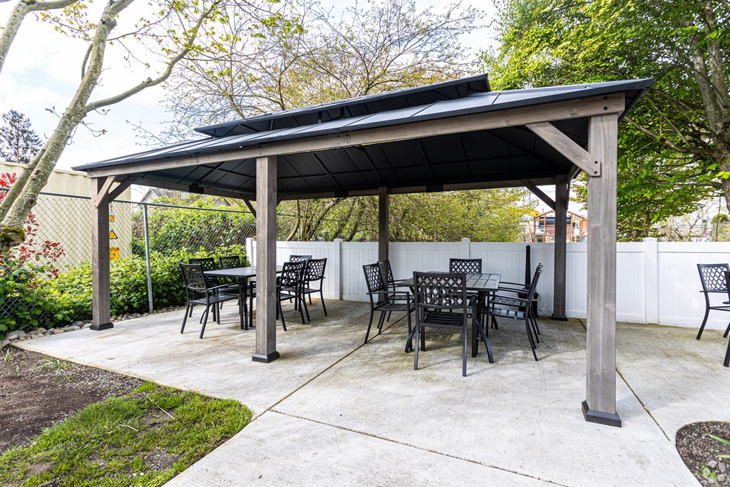 a patio with a table and chairs under a gazebo