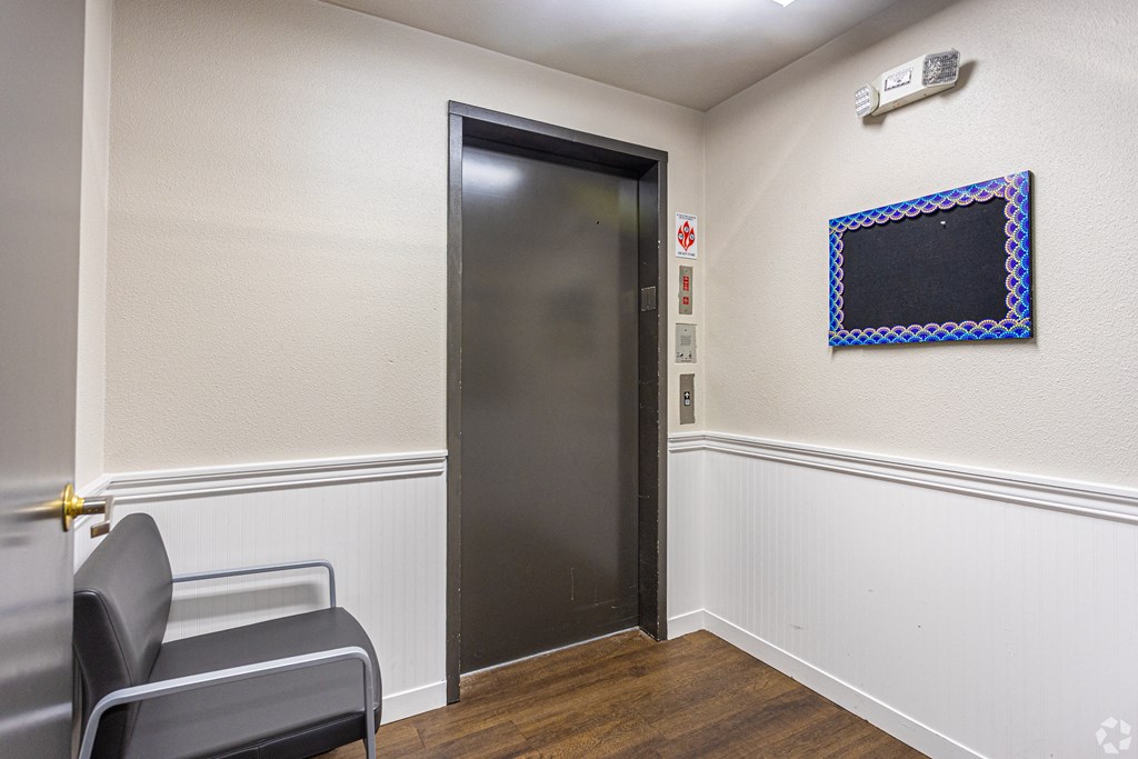 a room with a door to a elevator and two chairs